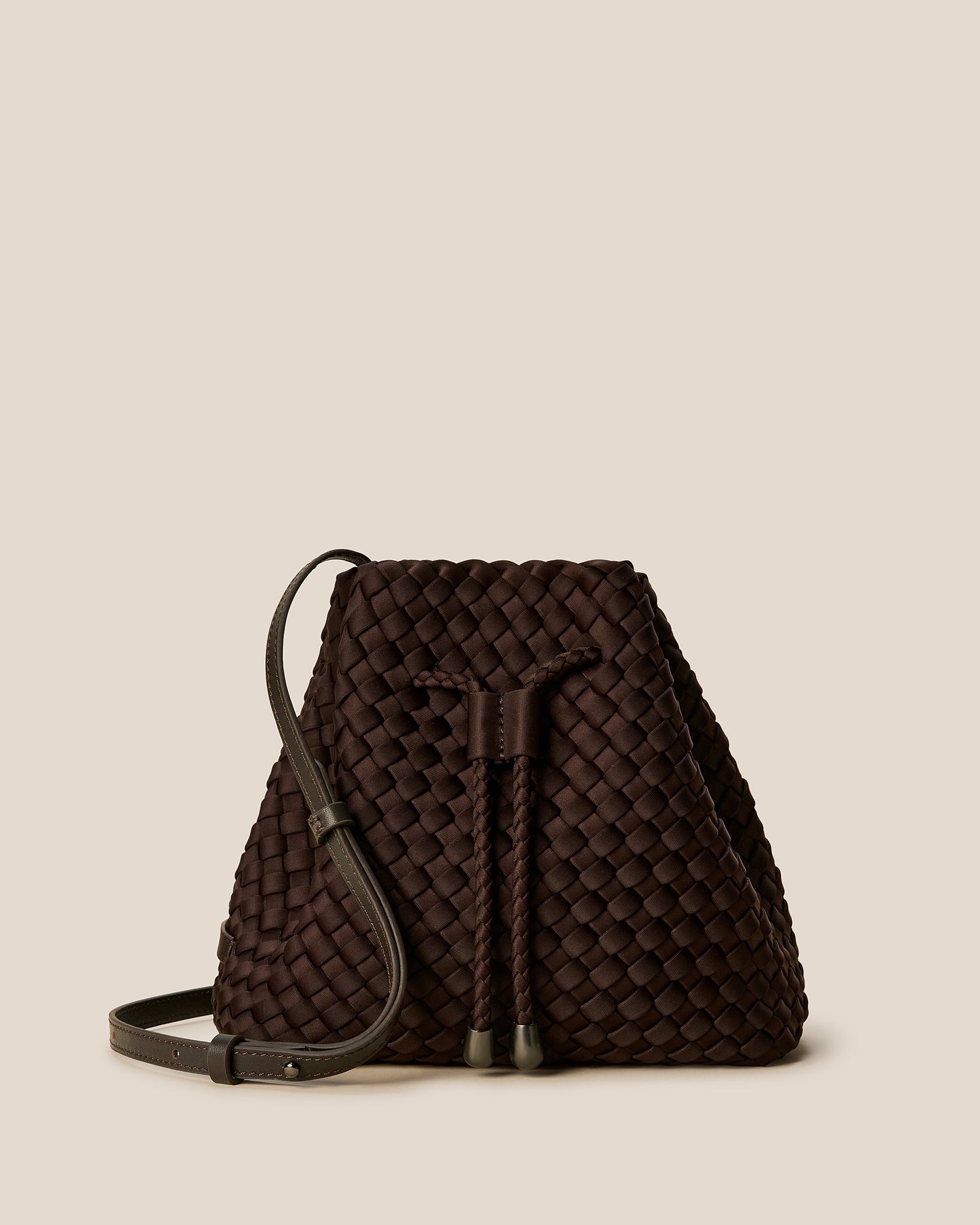 A rich chocolate-toned crossbody bucket bag featuring handwoven neoprene texture, drawstring closure, and adjustable leather strap—showcasing artisanal craftsmanship and tactile elegance by Valnera Vista