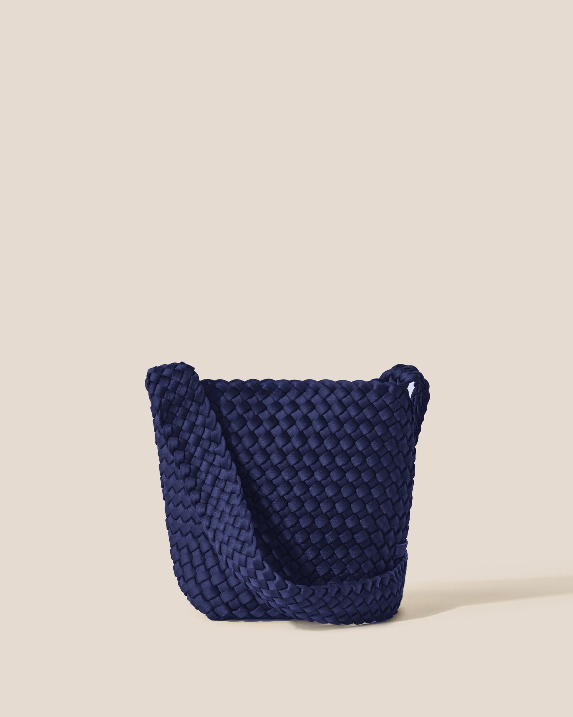 Valnera Vista Laguna ink blue crossbody bag with handwoven neoprene texture, deep navy hue, and slender strap—exuding coastal cool style with artisanal elegance