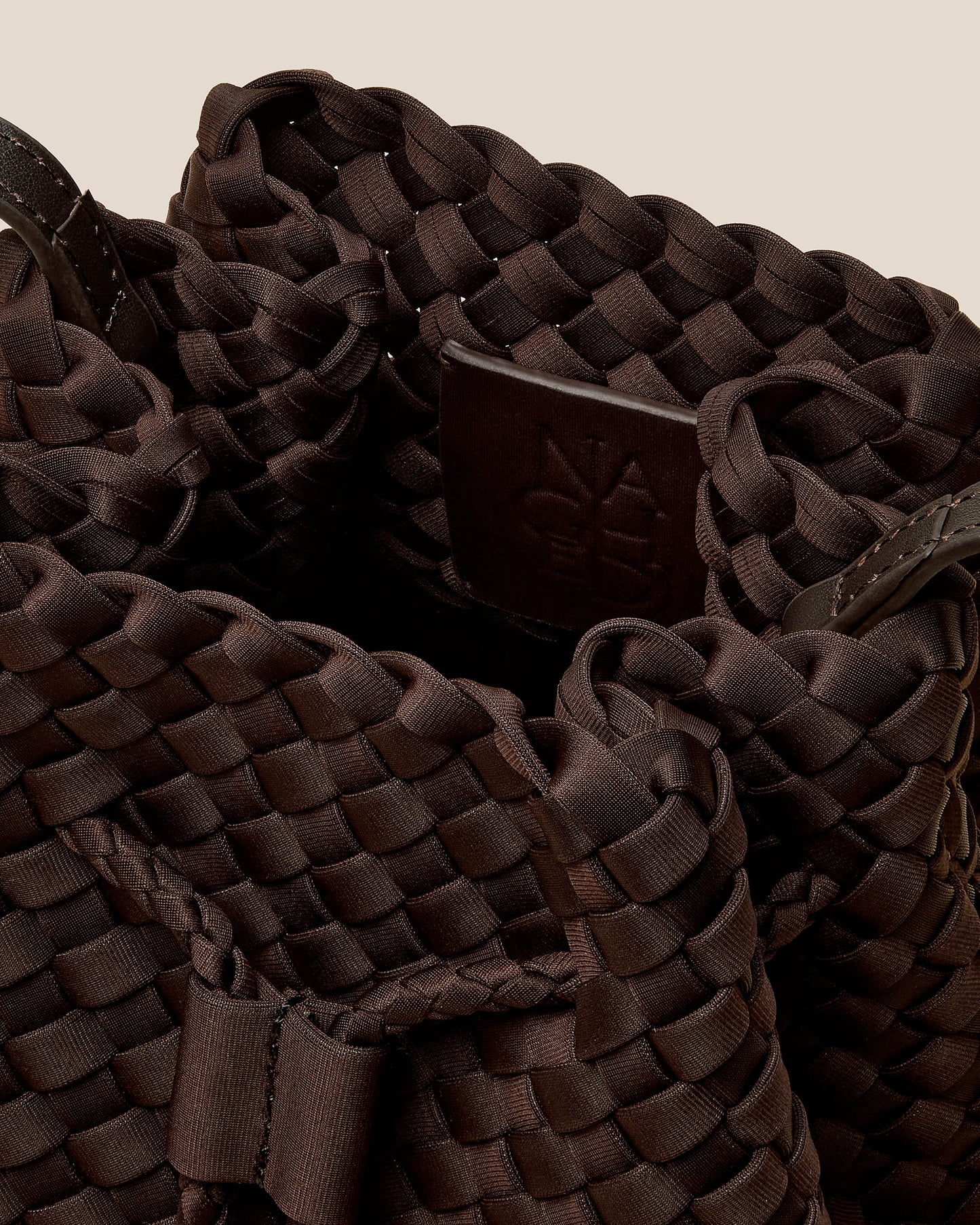 A rich chocolate-toned crossbody bucket bag featuring handwoven neoprene texture, drawstring closure, and adjustable leather strap—showcasing artisanal craftsmanship and tactile elegance by Valnera Vista-1