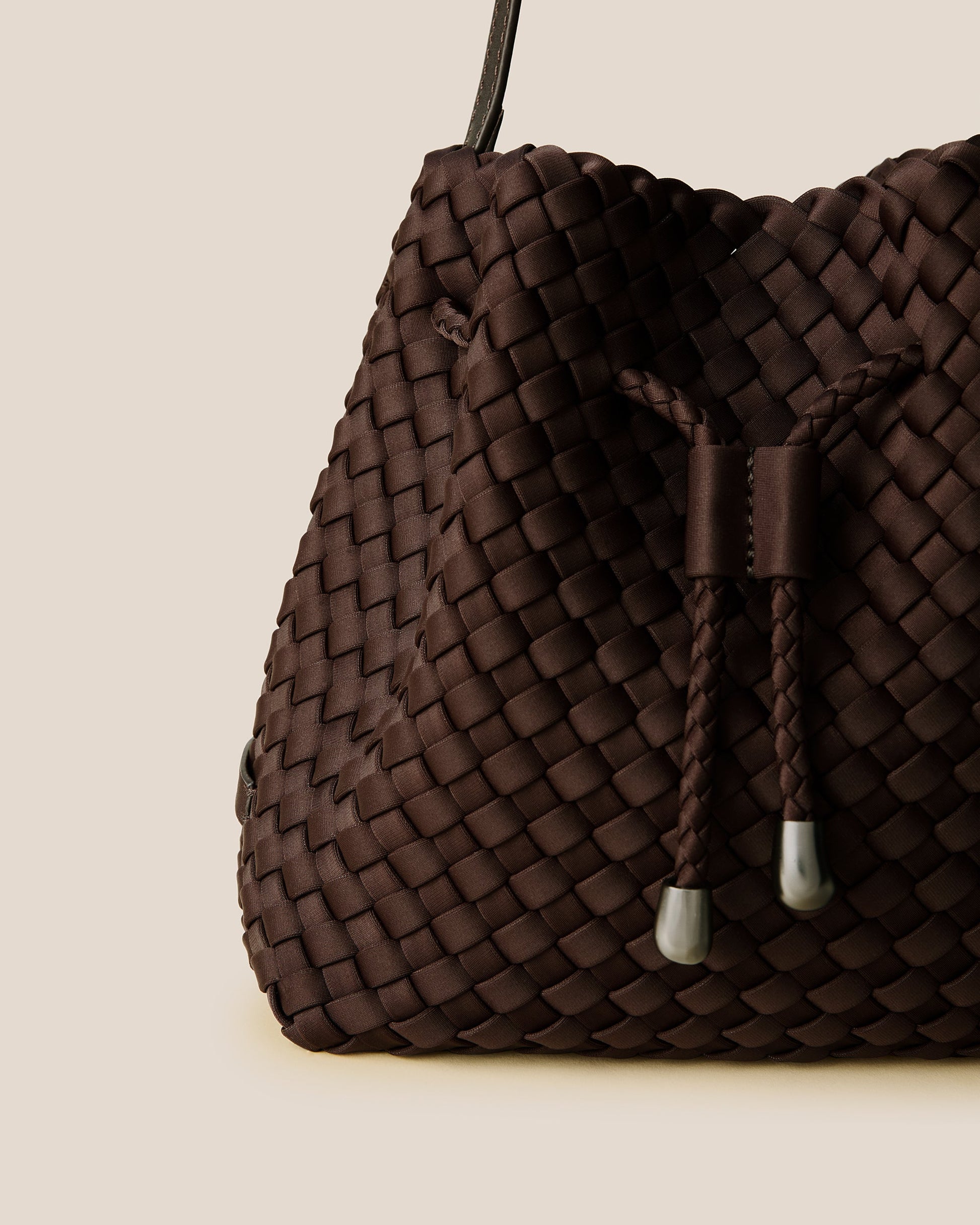 A rich chocolate-toned crossbody bucket bag featuring handwoven neoprene texture, drawstring closure, and adjustable leather strap—showcasing artisanal craftsmanship and tactile elegance by Valnera Vista-2